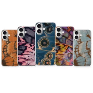 May include: Five smartphone cases arranged in a row, each featuring a distinct butterfly wing pattern. The designs include orange, pink and black, deep blue with circular eye spots, multicolored iridescent, and light blue with brown veins.