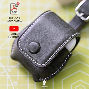 Peut inclure: Un étui de protection en cuir noir pour écouteurs sans fil avec des coutures contrastantes blanches, une fermeture à bouton-pression circulaire et une sangle avec une boucle en métal argenté. Le texte inclut PDF INSTANT DOWNLOAD et VIDEO TUTORIAL.