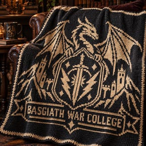 Può includere: Una coperta all'uncinetto nera e beige raffigurante un grande drago appollaiato sopra uno scudo con un emblema a spada. Il design include sagome di castelli sui lati e uno stendardo in basso con il testo BASGIATH WAR COLLEGE.