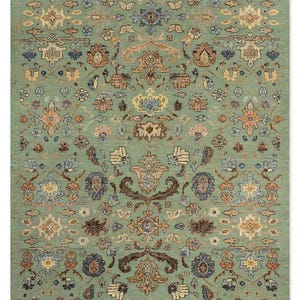 May include: A rectangular area rug featuring a sage green background with a repeating symmetrical pattern of floral and botanical motifs in shades of rust orange, navy blue, cream, and brown, creating a dense and intricate decorative design.