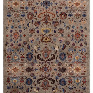 May include: A rectangular area rug featuring a taupe background with a repeating pattern of floral and geometric motifs in shades of blue, orange, yellow, and dark brown. The design is symmetrical, with intricate details distributed across the surface.