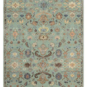 May include: A rectangular area rug featuring a light sage green background with a symmetrical, intricate floral and vine pattern in shades of terracotta, cream, dark brown, and muted blue, enclosed by a decorative border with repeating motifs.