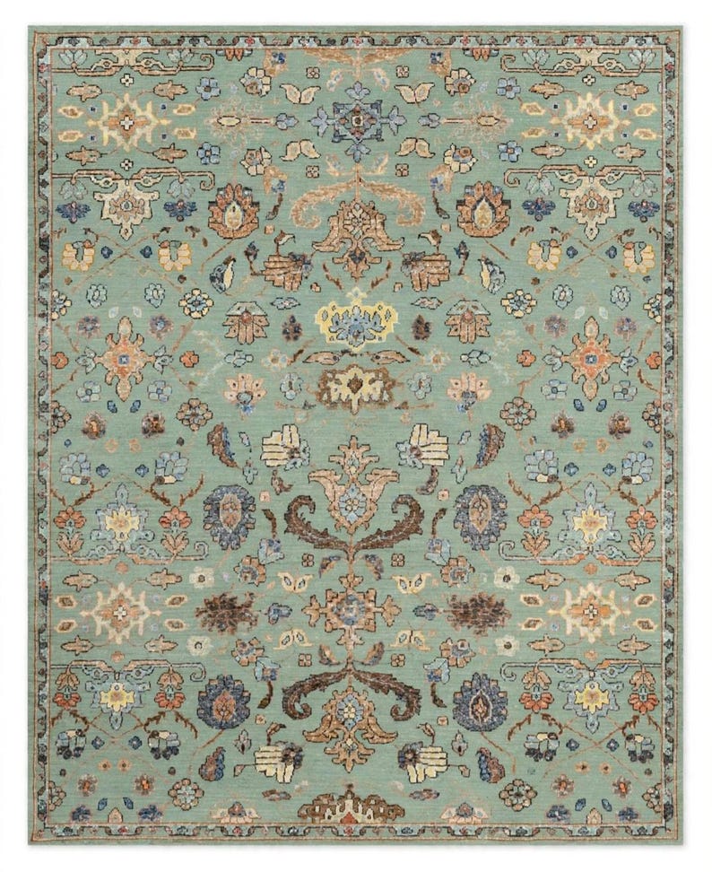 May include: A rectangular area rug featuring a light sage green background with a symmetrical, intricate floral and vine pattern in shades of terracotta, cream, dark brown, and muted blue, enclosed by a decorative border with repeating motifs.