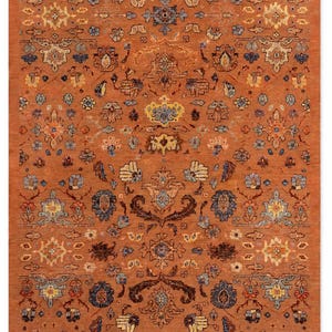 May include: A rectangular area rug featuring a deep burnt orange background with a repeating pattern of intricate floral and botanical motifs in shades of navy blue, light blue, cream, yellow, and dark brown, arranged in a symmetrical layout.