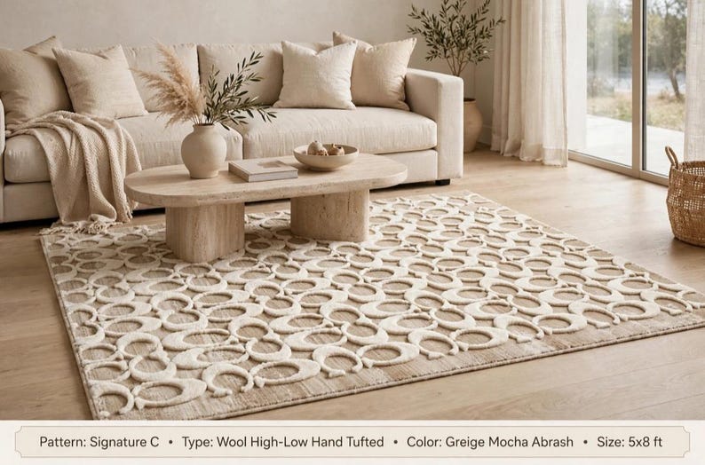 May include: A rectangular wool high-low hand-tufted rug featuring a repeating Signature C pattern in greige and mocha abrash colors. The rug measures 5x8 ft and displays a textured surface with raised cream-colored letter C motifs.