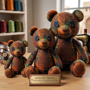 May include: Three stuffed bears made from plaid fabric with orange, blue, and green tones, featuring embossed mandala patterns. A wooden sign in front reads: MEMORY BEARS: AVAILABLE IN 3 SIZES (S, M, L). Each bear has a small metal tag on its ear.