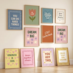 May include: A collection of eleven rectangular wall art prints in light wood frames, featuring various motivational quotes and colourful graphic designs including flowers, hearts, and stars in shades of blue, pink, yellow, green, and orange.