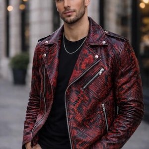 Peut inclure: Une veste de motard en cuir à motif peau de serpent rouge et noir, dotée de fermetures éclair en métal argenté, d'un revers cranté avec boutons-pression et de manches longues. Portée sur un t-shirt noir uni avec une fine chaîne en argent.