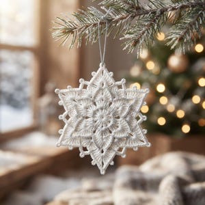 May include: A white crocheted snowflake ornament with intricate, star-shaped patterns and subtle silver metallic thread accents. The ornament is suspended by a thin silver string, featuring a symmetrical, multi-layered design with pointed edges.