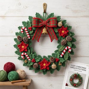 May include: A crocheted Christmas wreath featuring green leaves, red poinsettia flowers, brown pinecones, red and white candy canes, and small gold ornaments. A large red and green plaid bow with a gold bell hangs at the top center.