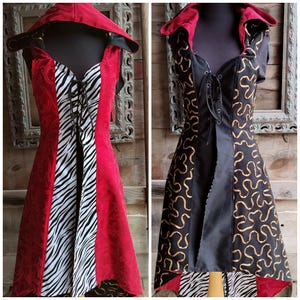 May include: Two sleeveless hooded dresses with front lace-up closures. The left dress is red with a black and white zebra print center panel. The right dress is black with a gold squiggly line pattern and a red interior hood lining.