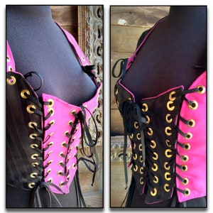 May include: A black and pink corset with gold eyelets and black laces. The corset is made of a striped fabric and has a pink lining.
