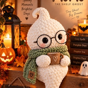 Puede incluir: Un peluche de fantasma tejido en color blanco con gafas negras redondas y una bufanda de punto verde, sosteniendo una pequeña taza marrón con un corazón. El texto dice MOMO THE SHELF GHOST, Tiny Ghost Big Dreams, Spooky Moments Brighter Days y Happy Halloween.