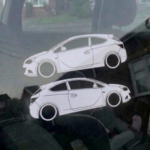 May include: Two white vinyl car decals applied to a glass surface. Each decal features the line art silhouette of a three-door hatchback vehicle, showing the side profile with detailed outlines of the windows, doors, and circular wheel wells.
