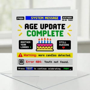 Op de afbeelding: Een vierkante wenskaart met een witte achtergrond voorzien van pixel art afbeeldingen en tekst. Het ontwerp bootst een computersysteembericht na met de tekst AGE UPDATE COMPLETE, een verjaardagstaart en foutmeldingen zoals Error 404: Youth not found.