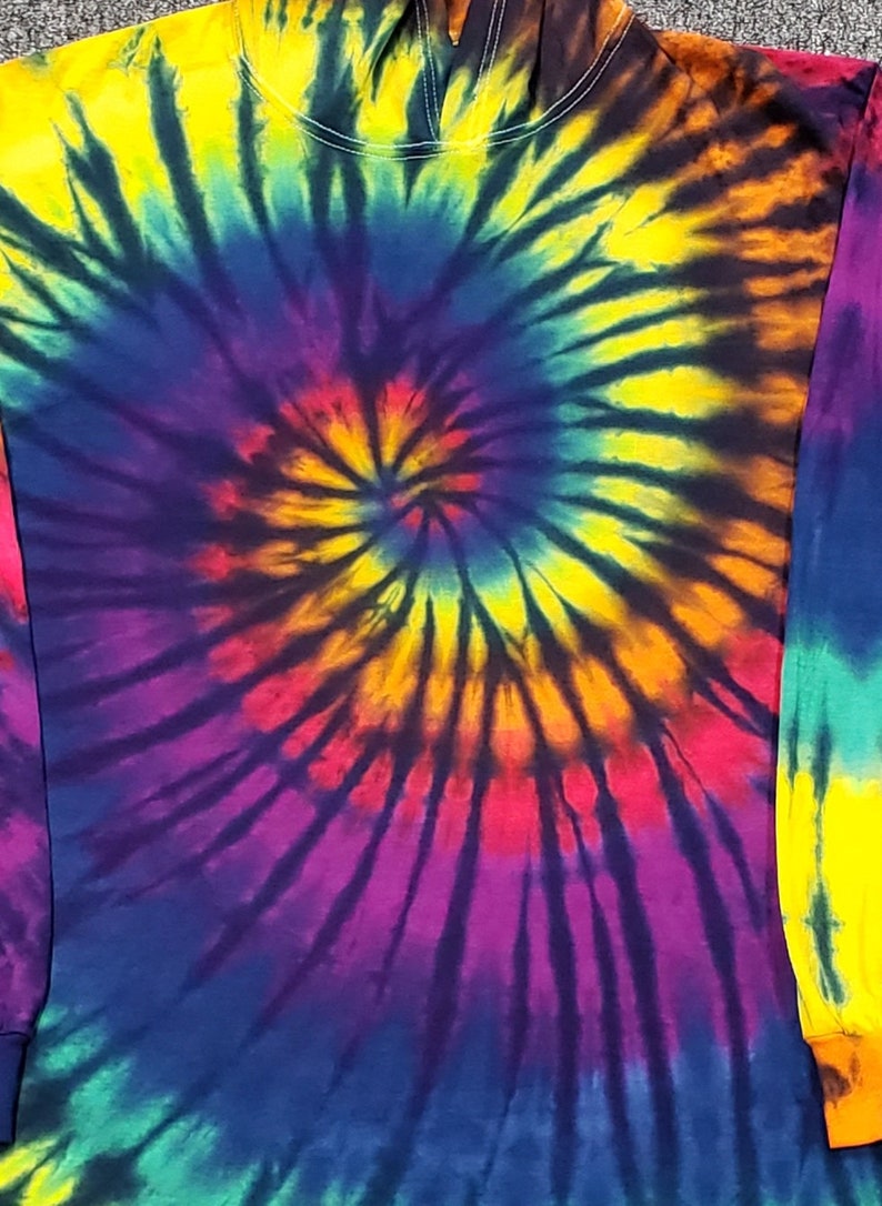 Peut inclure: Un sweat &agrave; capuche tie-dye &agrave; manches longues avec un motif en spirale dans des tons de jaune, orange, rouge, violet, bleu, vert et noir.