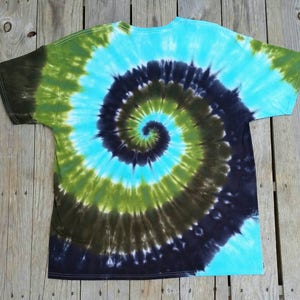 Puede incluir: Una camiseta tie-dye con un patr&oacute;n de espiral azul, verde y negro.