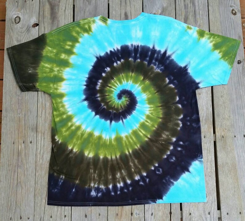 Puede incluir: Una camiseta tie-dye con un patr&oacute;n de espiral azul, verde y negro.