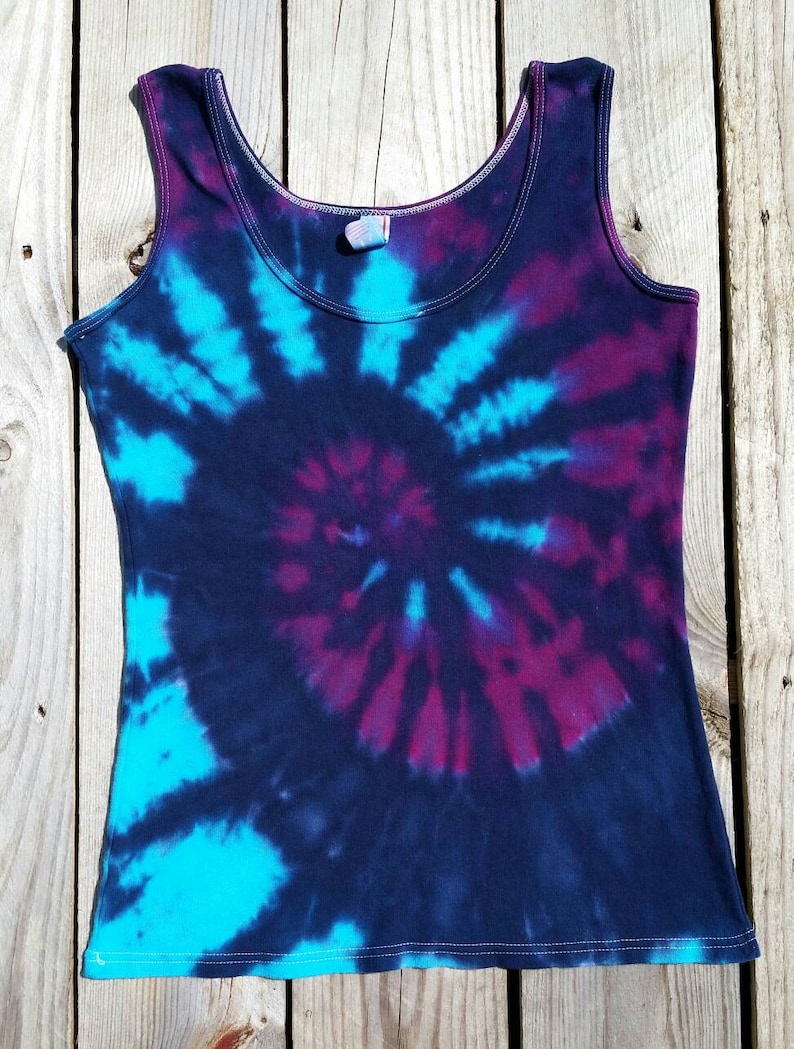 Pu&ograve; includere: Un top a canotta tie-dye con un motivo a spirale in tonalit&agrave; di blu, viola e nero.