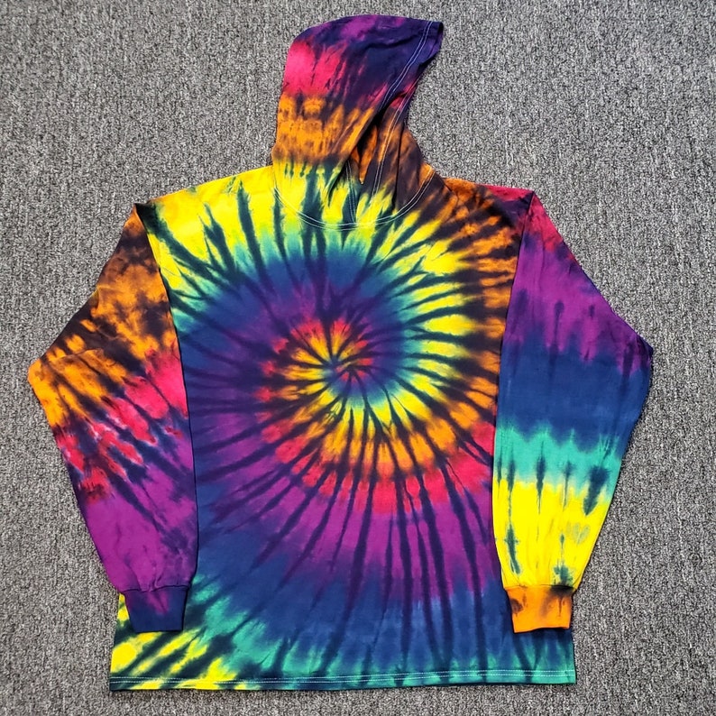Peut inclure: Un sweat &agrave; capuche tie-dye &agrave; manches longues avec un motif tourbillonnant de violet, jaune, orange et bleu.