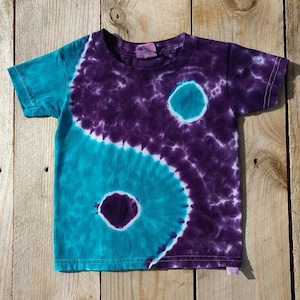 May include: A tie-dye t-shirt with a purple and teal yin-yang design.