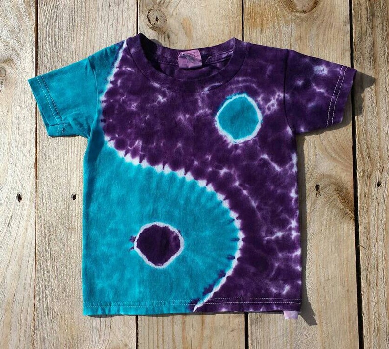May include: A tie-dye t-shirt with a purple and teal yin-yang design.
