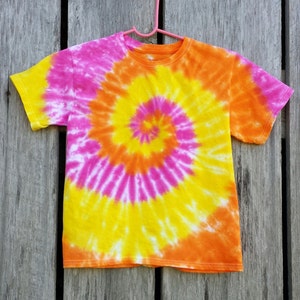 May include: A tie-dye t-shirt with a spiral pattern in shades of pink, yellow, and orange.