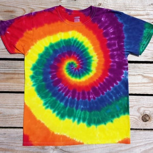 May include: A short-sleeved, crew neck t-shirt with a vibrant tie-dye spiral pattern. The design features a rainbow of colors, including red, orange, yellow, green, blue, and purple. The shirt is made of a soft material.