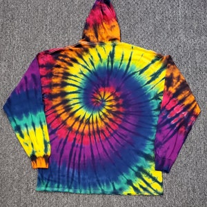 Peut inclure: Un sweat &agrave; capuche tie-dye &agrave; manches longues avec un motif tourbillonnant de jaune, orange, rouge, violet, bleu et vert.