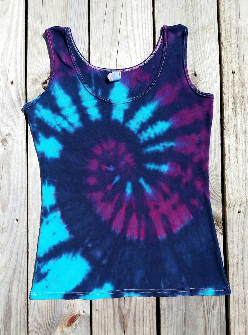 Pu&ograve; includere: Un top nero senza maniche con un motivo tie-dye in tonalit&agrave; blu e viola.