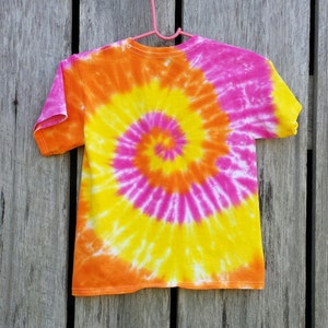 May include: A tie-dye t-shirt with a spiral pattern in shades of pink, orange, and yellow.