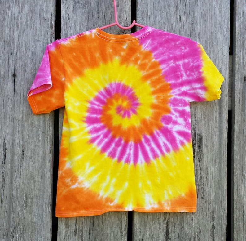 May include: A tie-dye t-shirt with a spiral pattern in shades of pink, orange, and yellow.