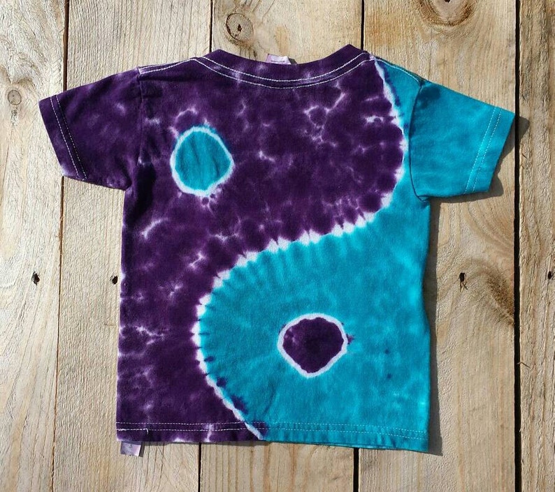 May include: A purple and teal tie-dye t-shirt with a yin yang design.