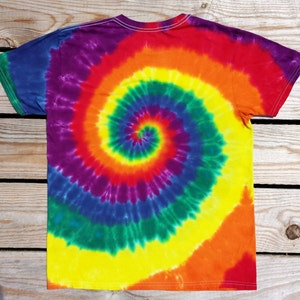 May include: A colorful tie-dye t-shirt with a spiral pattern. The shirt features a vibrant blend of rainbow colors, including red, orange, yellow, green, blue, and purple. The shirt is made of soft material and has a classic crew neck.