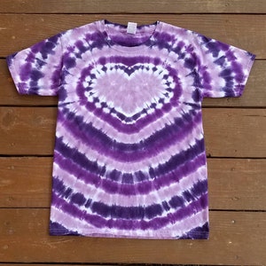 May include: Purple tie-dye t-shirt with a white heart design in the center.