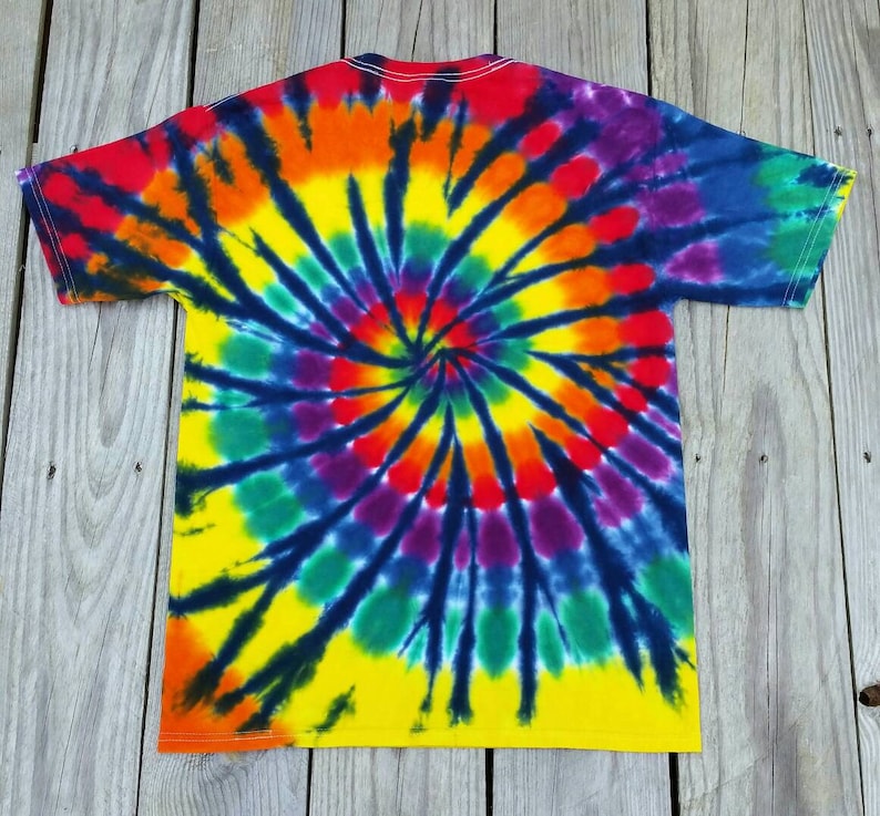 Może przedstawiać: Koszulka tie-dye z wzorem spiralnym w odcieniach czerwieni, pomarańczy, ż&oacute;łci, zieleni, błękitu, fioletu i czerni.