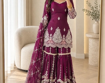 May include: A deep purple three-piece outfit featuring a short-sleeved kurta with silver embroidery, matching flared sharara trousers with intricate silver detailing, and a sheer matching dupatta with embroidered borders, labelled Meherzaa Clothing.
