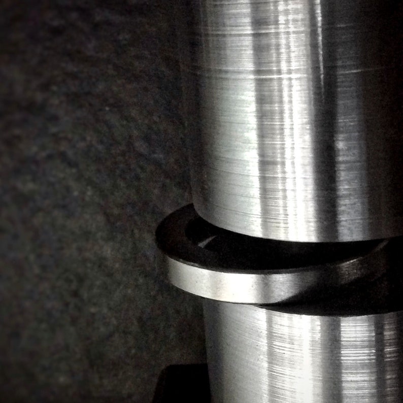 May include: Close-up of a silver metal rod with a smooth, shiny surface. The rod is surrounded by a silver metal ring.