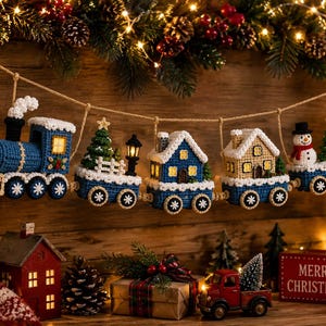 Puede incluir: Una guirnalda de tren navideño tejida a ganchillo con una locomotora azul, dos vagones en forma de casa y un último vagón con un muñeco de nieve y un árbol. El tren está suspendido por una cuerda y decorado con bordes blancos.