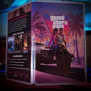 May include: A Grand Theft Auto VI video game case featuring a purple and orange sunset background with palm trees. The cover art displays two characters sitting on the hood of a car. The back cover includes French text, game details, and imagery.