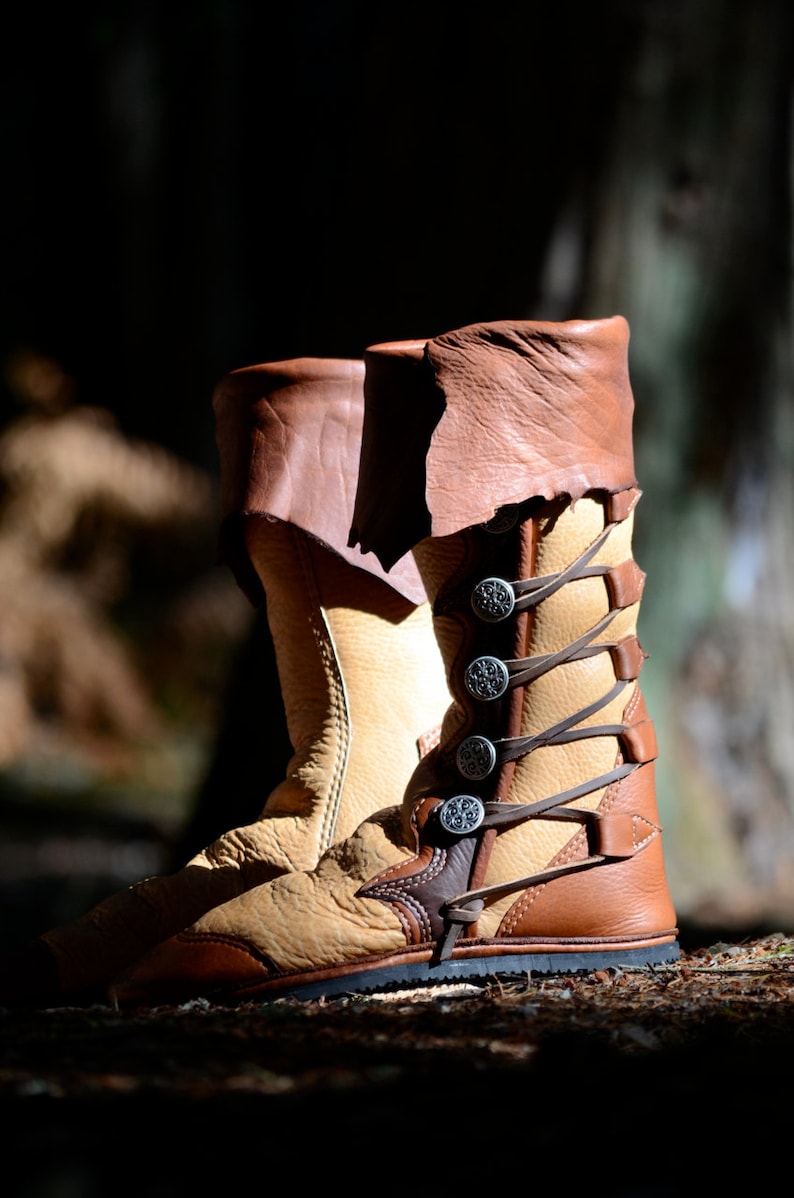 May include: A pair of brown leather boots with decorative metal buckles and laces. The boots are worn and have a distressed look.