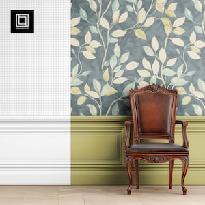 May include: A brown leather armchair with carved wooden legs and arms sits in front of a wall with a blue and green floral wallpaper. The wall has a white wainscoting with a green baseboard.