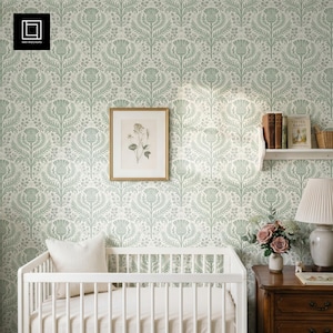 Pode incluir: Um quarto de criança com um berço branco, uma impressão botânica emoldurada e uma mesa de cabeceira de madeira. As paredes são cobertas com papel de parede floral verde claro e branco. Uma lâmpada branca e um buquê de flores cor-de-rosa completam a decoração.