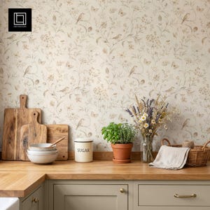 Puede incluir: Una escena de cocina con tablas de cortar de madera, cuencos y un azucarero. Una planta de hierbas en maceta y un ramo de flores se encuentran sobre una encimera de madera. El fondo es un papel pintado floral con pájaros y mariposas.