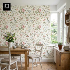 May include: A dining room with a wooden table and chairs, set against a floral wallpaper. The wallpaper features a pattern of pink roses, green leaves, and other small flowers. A vase of flowers sits on the table, with a window in the background.