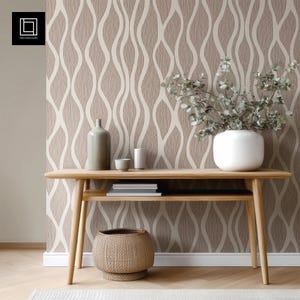 May include: A wooden console table with a lower shelf, holding books and decorative items. A white vase with greenery sits on the table. The background features a textured wallpaper with a beige and white wavy pattern.