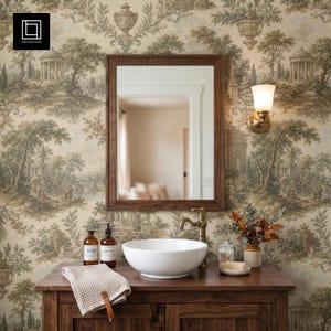May include: A rectangular wooden mirror hangs above a dark wood vanity featuring a white ceramic vessel sink, a brass faucet, and a folded beige towel. The wall is covered in wallpaper with a sepia-toned landscape pattern and a wall sconce.