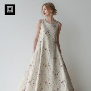 Może przedstawiać: Kremowa sukienka bez rękawów z kwiatowym wzorem w odcieniach fioletu i zieleni. Sukienka ma kształt litery A i okrągły dekolt. Tkanina ma fakturę.