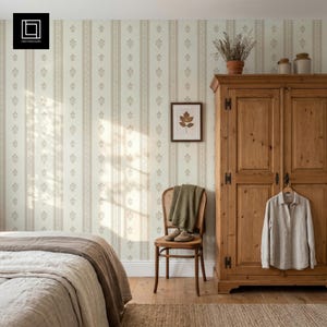 May include: A bedroom scene featuring wallpaper with vertical stripes and small floral motifs in beige and white. A wooden wardrobe stands to the right with a light-colored shirt hanging on the door. A wooden chair holds a green cloth and shoes.