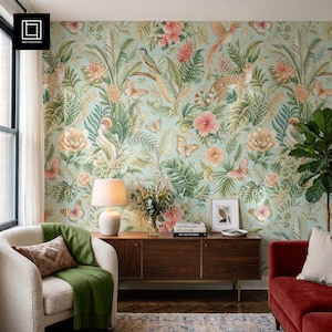 Könnte beinhalten: Eine hellgrüne Tapete mit einem dichten tropischen Muster aus rosa Hibiskusblüten, üppigen grünen Palmenblättern, Schmetterlingen und einem Leoparden. Eine weiße Tischlampe, ein hölzernes Sideboard und ein gerahmter Druck stehen vor der Wand.